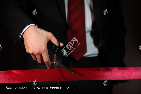 用剪刀切一個紅絲帶的商人