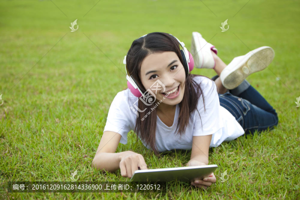 年輕女性在草地上使用平板電腦