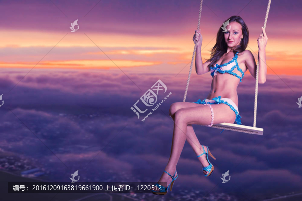 在天空背景下獨(dú)自蕩秋千的年輕女子