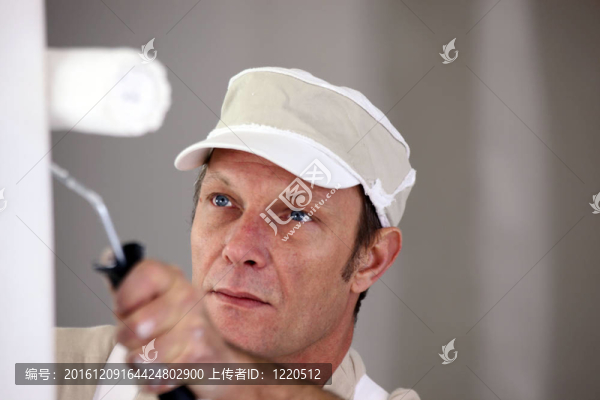 墻上使用油漆輥的人