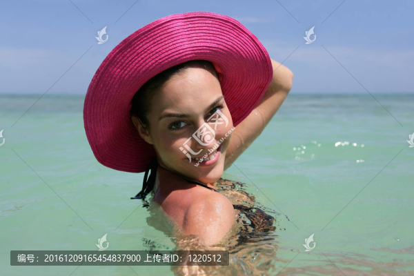 海灘上戴著粉紅色帽子的女人