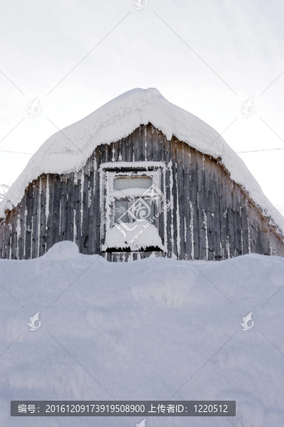 在寒冷的冬日午后，一個(gè)蓋著雪的小木屋的屋頂和窗戶
