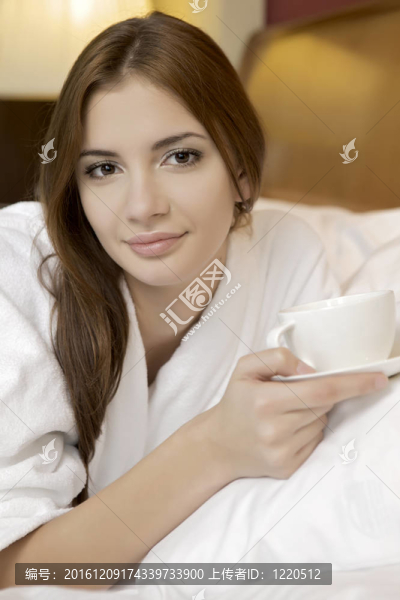 美麗的女人與杯子在床上