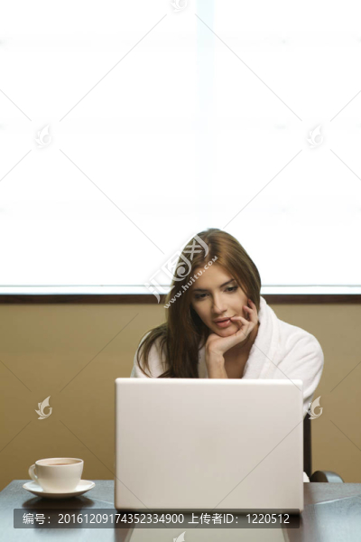 年輕女人看著她的筆記本電腦，喝著咖啡