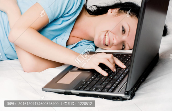 漂亮的女孩在床上有筆記本電腦