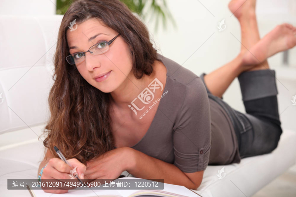 戴眼鏡的年輕女子赤腳躺在沙發(fā)上看書
