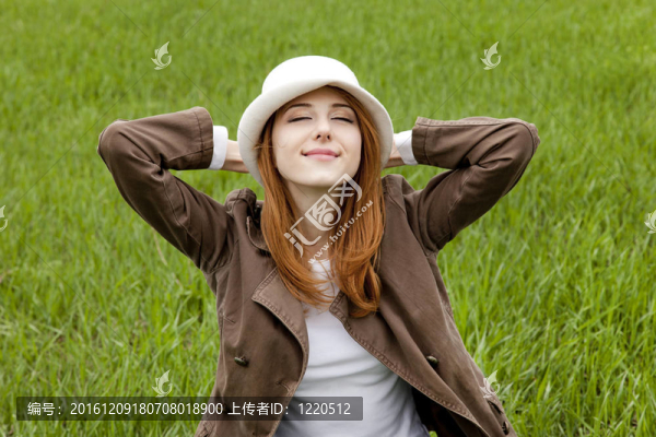 在綠色的春天的草在白色帽子的年輕時尚的女孩。