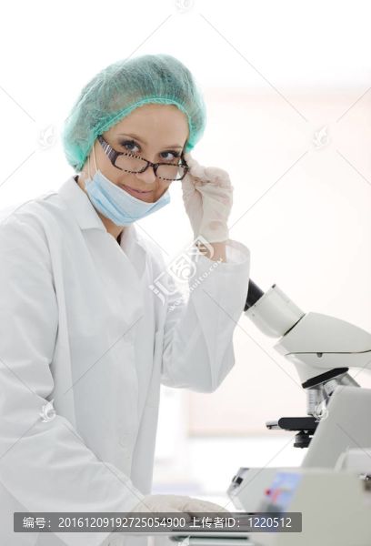 年輕女性研究人員在實驗室看顯微鏡和筆記本筆記