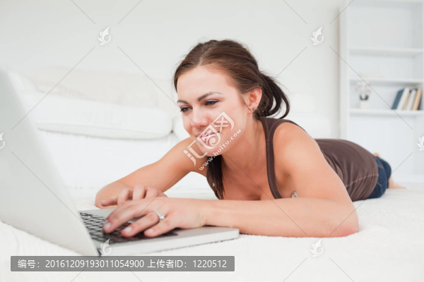 可愛(ài)的女人躺在地毯上用筆記本電腦