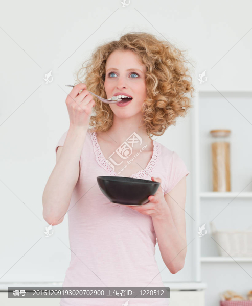 漂亮的金發(fā)女人在廚房里吃一碗麥片