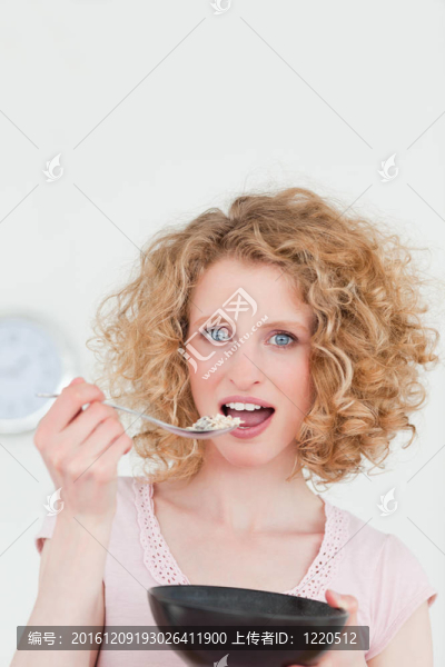 漂亮的金發(fā)女人在廚房里吃一碗麥片