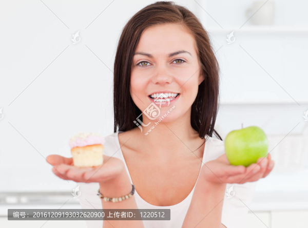 年輕女人拿著一個(gè)蘋(píng)果和一塊蛋糕