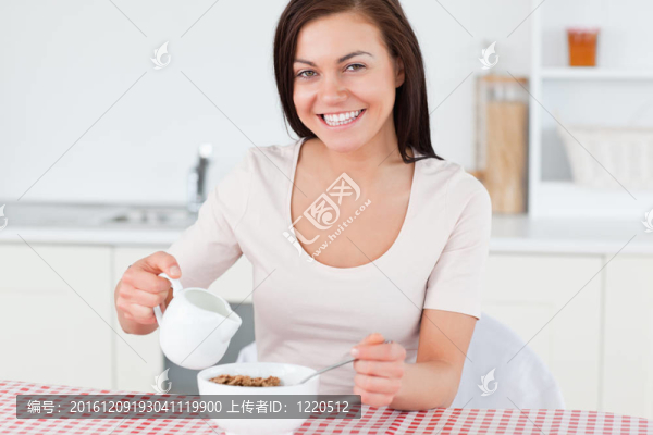 年輕女人在麥片里倒牛奶