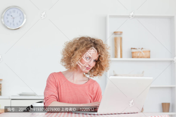 可愛的金發(fā)女人放松她的筆記本電腦坐在她公寓的廚房