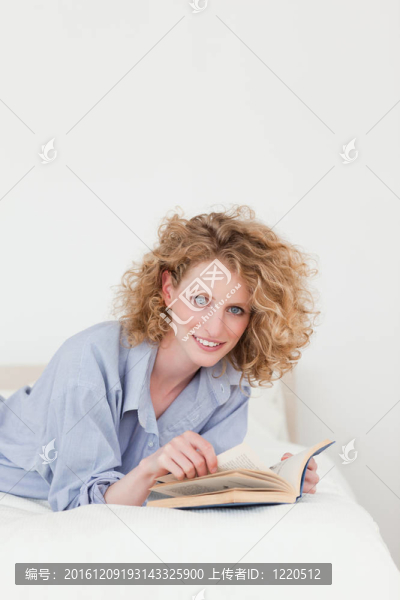迷人的金發(fā)女子躺在床上看書