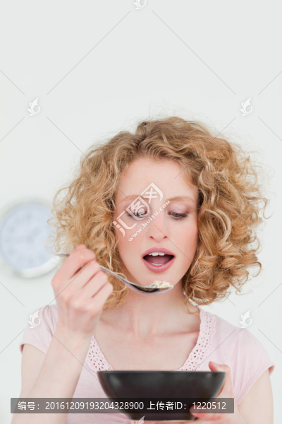 漂亮的金發(fā)女人吃一碗麥片在她公寓的廚房