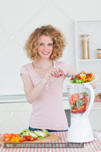 迷人的金發(fā)女人在廚房里使用攪拌機(jī)