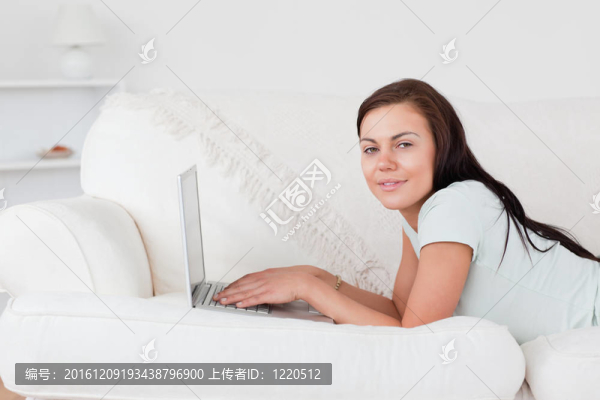 可愛(ài)的女人在沙發(fā)上用筆記本電腦