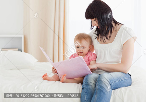 美麗的黑發(fā)女子展示一本書給她的孩子而坐