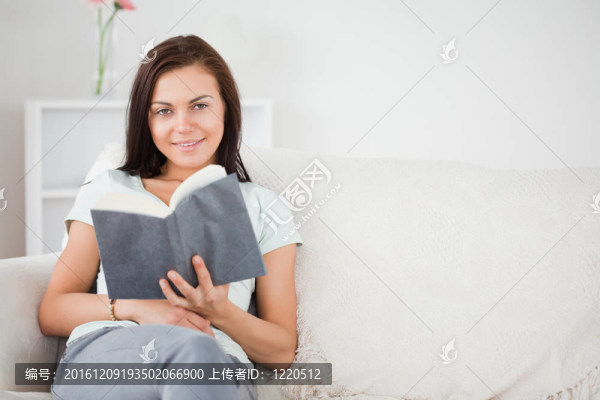 可愛的黑發(fā)女子拿著書一邊看著相機(jī)