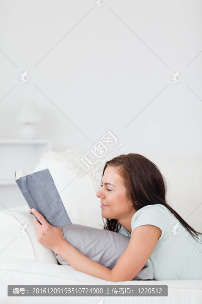 迷人的女人在沙發(fā)上看書(shū)