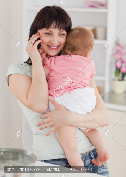 可愛(ài)的女人在電話里抱著她的嬰兒