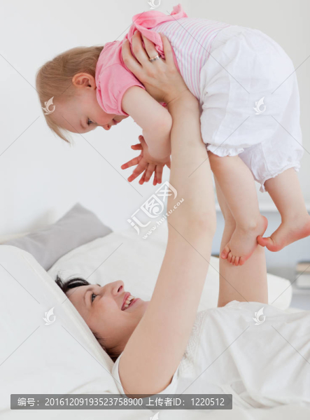 美麗的黑發(fā)女人玩她的寶寶躺在她的公寓床