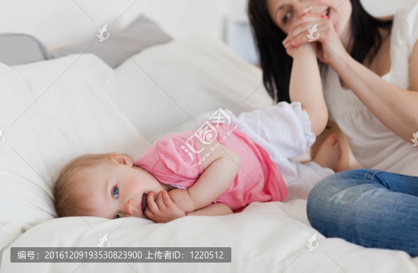 漂亮的黑發(fā)女玩她的寶寶躺在她的公寓床