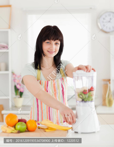 美麗的黑發(fā)女人用攪拌機(jī)站立