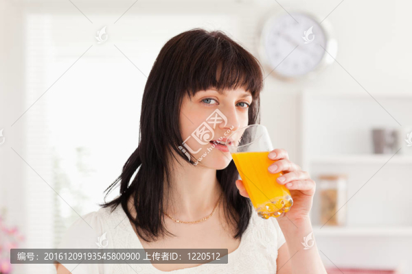 漂亮的黑發(fā)站在喝一杯橙汁