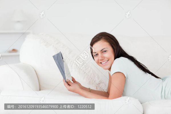 輕松的女人在沙發(fā)上拿著一本書