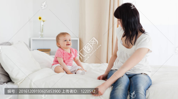 漂亮的黑發(fā)女人享受片刻與她的孩子坐在她的公寓床