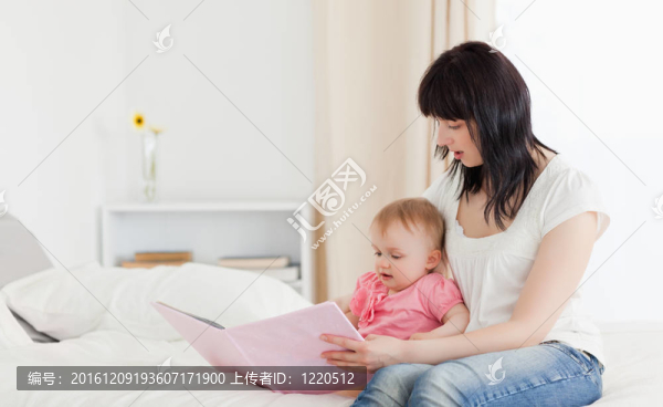 漂亮的黑發(fā)女子展示給她一本書(shū)，寶寶坐在她的公寓床