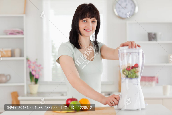 迷人的黑發(fā)女人用攪拌機(jī)站立