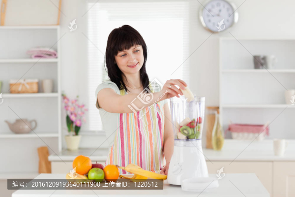 美麗的黑發(fā)女人把蔬菜放在一個(gè)攪拌機(jī)