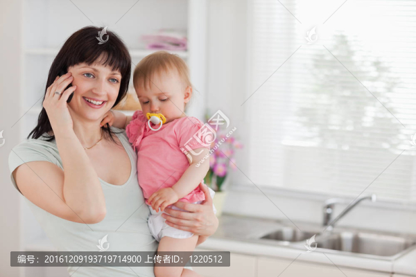 漂亮的女人在電話里抱著她的嬰兒