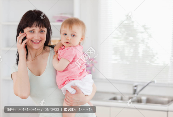 美麗的女人在電話里抱著她的嬰兒