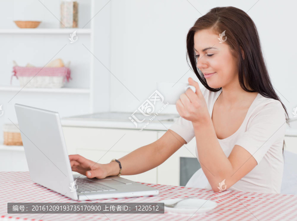 黑發(fā)婦女用筆記本電腦喝茶