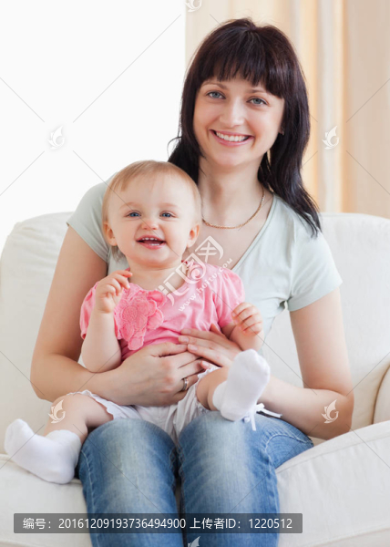 漂亮的女人抱著孩子坐在客廳的沙發(fā)上