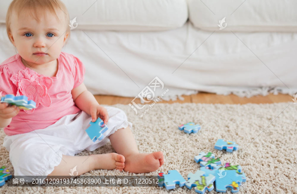 可愛(ài)的嬰兒玩拼圖碎片，而坐在客廳的地毯上