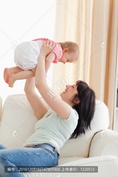 華麗的婦女抱著她的嬰兒在她的懷抱，而坐在客廳的沙發(fā)上