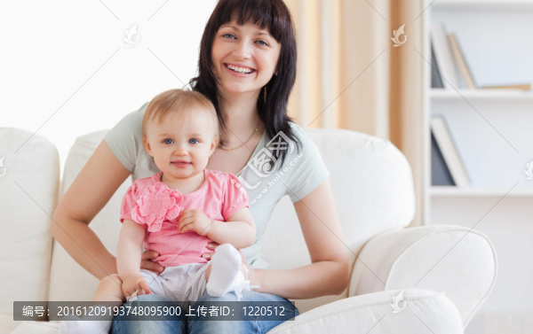 漂亮的女人抱著她的孩子坐在她的懷里