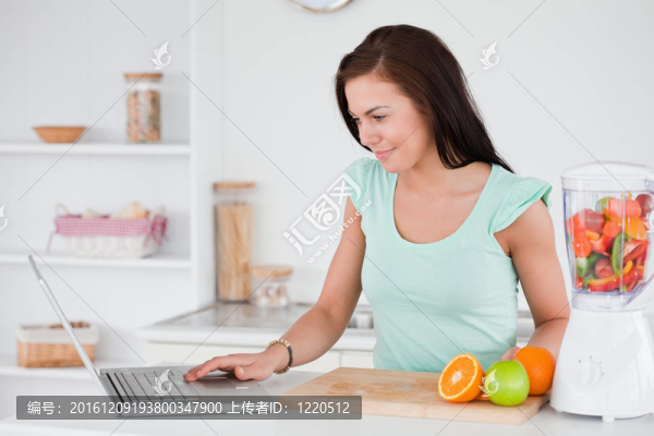 婦女與筆記本電腦和水果在攪拌機(jī)
