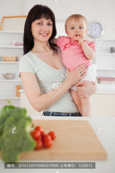 漂亮的女人抱著她的嬰兒站在她的懷里