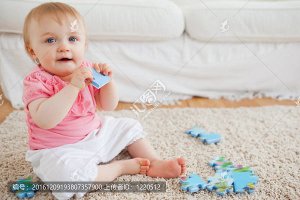 可愛的金發(fā)嬰兒玩拼圖碎片，而坐在客廳的地毯上