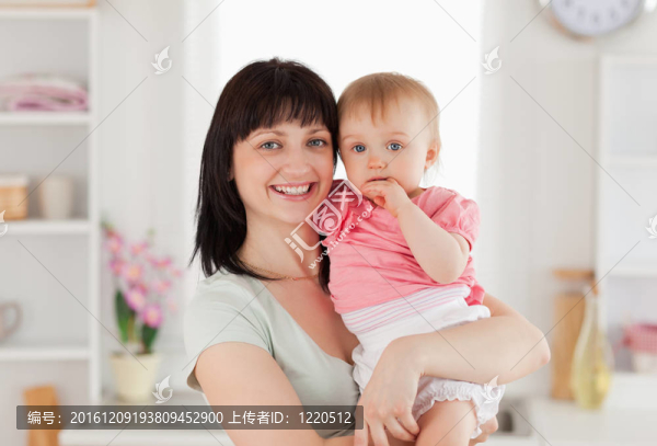 美麗的女人抱著她的嬰兒站在她的懷里