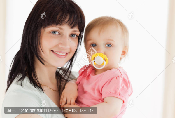 迷人的女人抱著她的嬰兒站在她的懷里