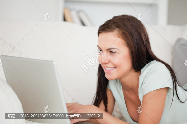 關閉了在沙發(fā)上使用筆記本電腦的一個可愛的女人