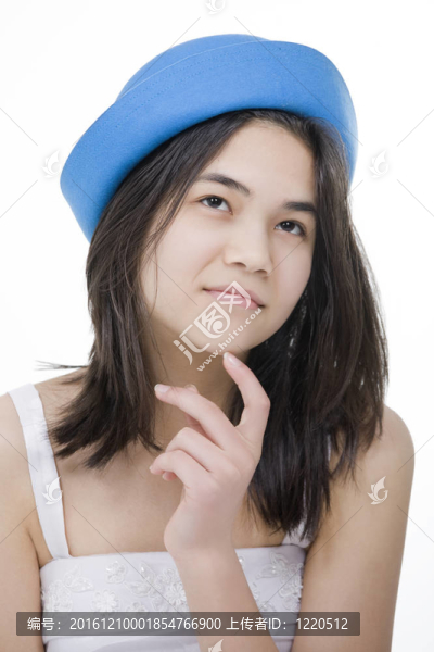 漂亮的戴著藍(lán)色帽子的年輕少女；用若有所思的表情仰望；手指觸摸下巴。