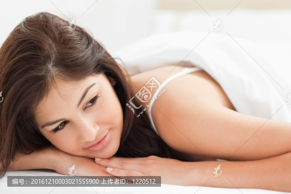 一個(gè)女人在被子下的特寫鏡頭，看著她的頭靠在她手上。
